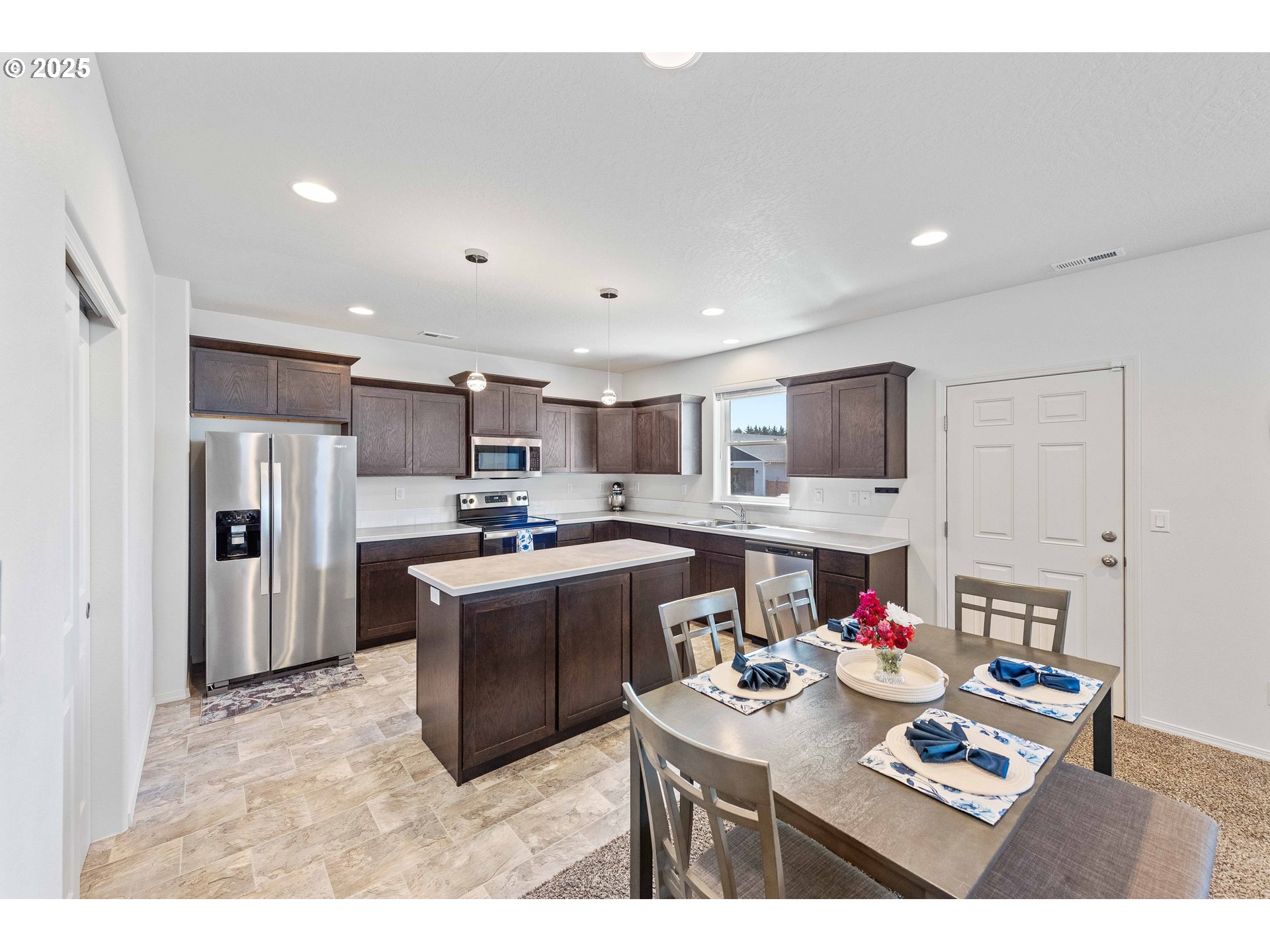 764 Seacrest Drive Bandon, OR 97411 - Photo 8 of 43 a open kitchen with stainless steel appliances kitchen island granite countertop a sink dishwasher and white cabinets with wooden floor