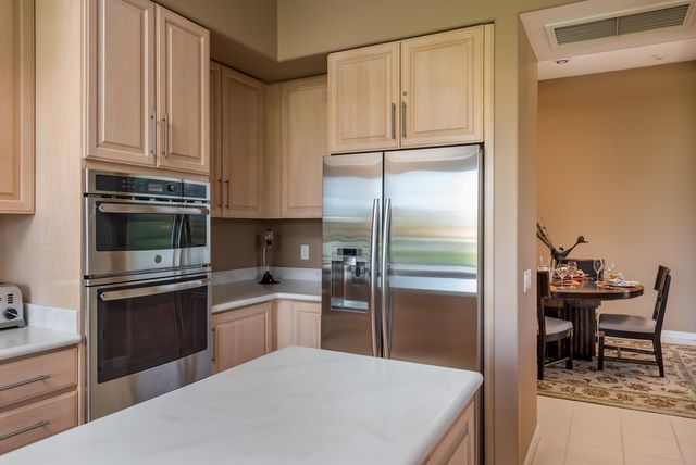 a kitchen with kitchen island granite countertop a refrigerator a stove a sink and a microwave