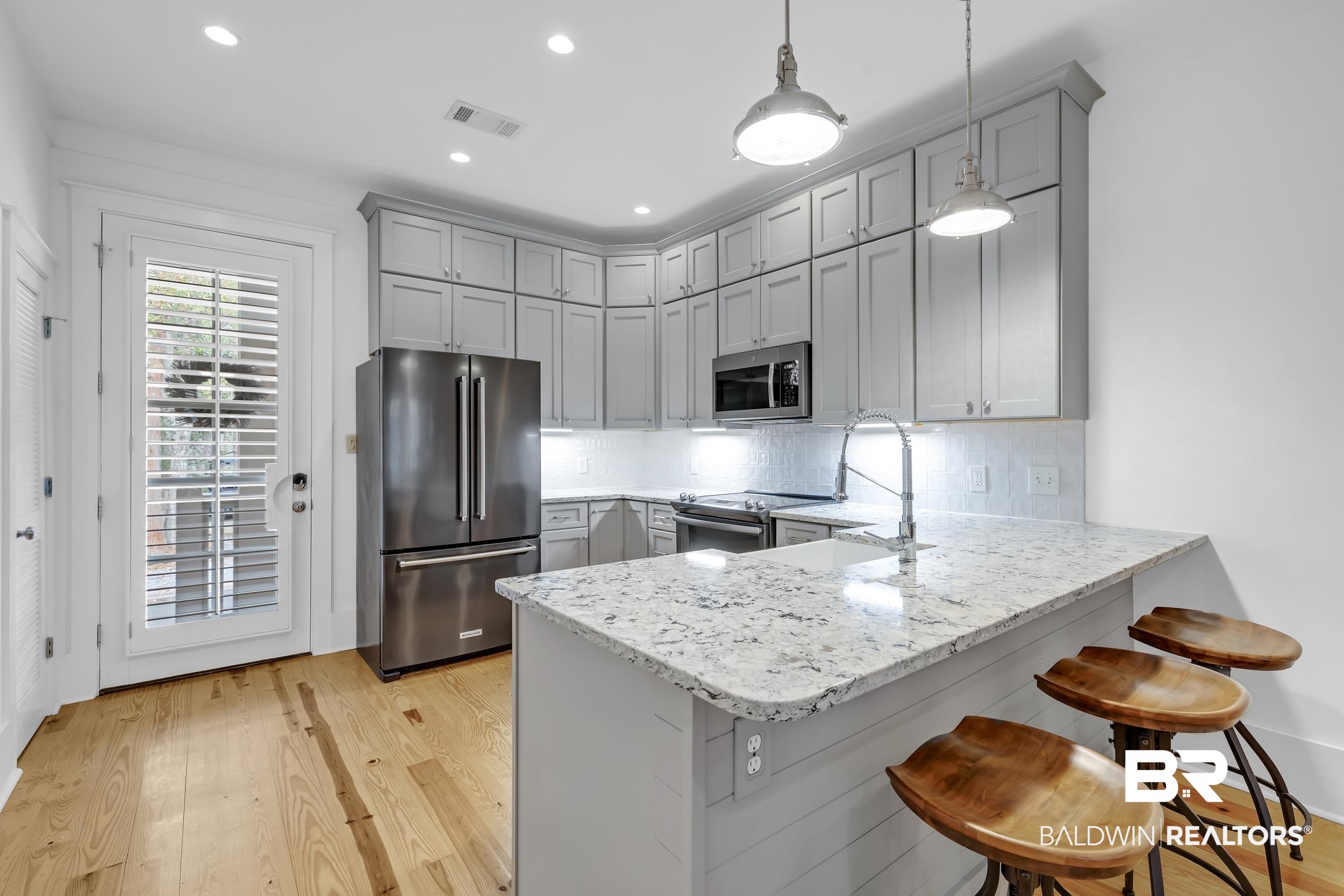 25773 Canal Road, Unit 32 Orange Beach, AL 36561 - Photo 6 of 35 Kitchen with stainless steel appliances, a breakfast bar area, a peninsula, light stone countertops, and light wood finished floors