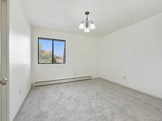an empty room with a chandelier fan and windows