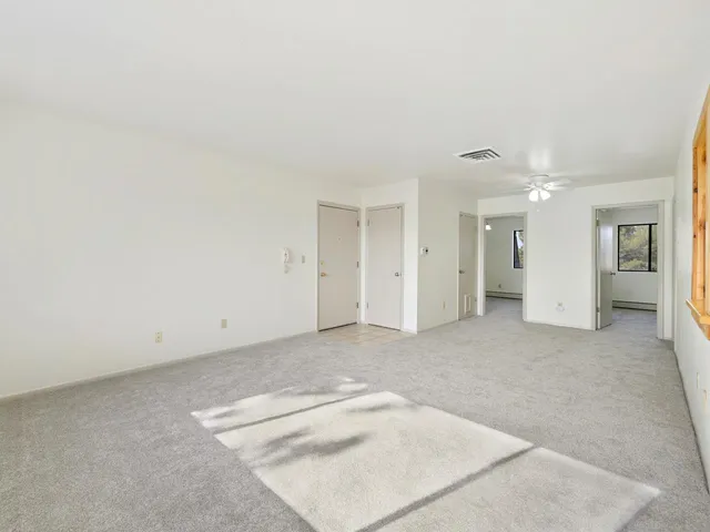 an empty room with a white wall and closet