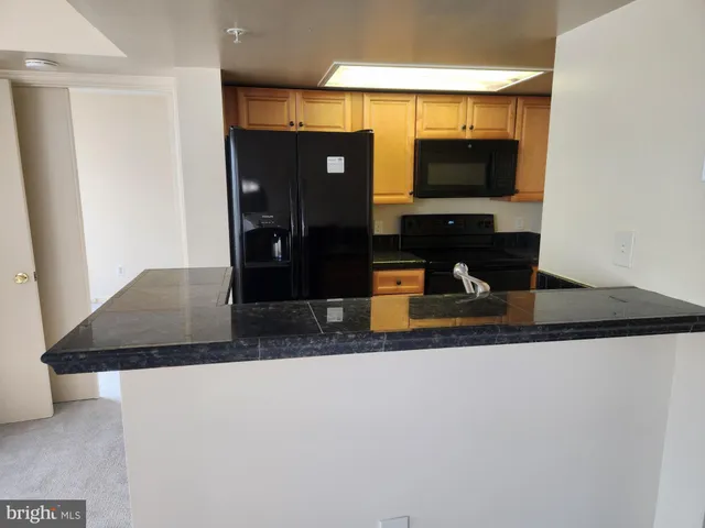 a living room with stainless steel appliances wooden floor and a counter top space