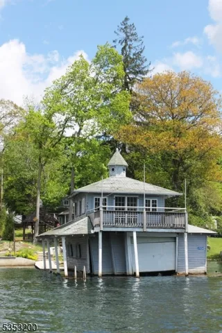 a front view of house with yard swimming pool and trees in the background