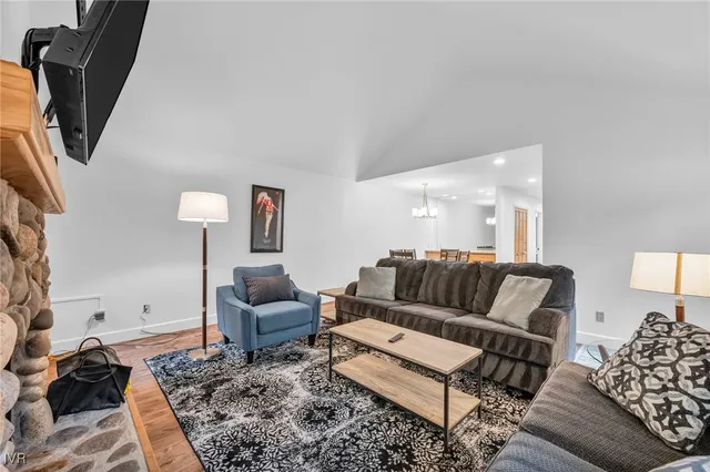 a view of a dining room and livingroom with furniture wooden floor a chandelier