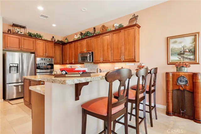 a kitchen with granite countertop a table chairs stove top oven and refrigerator