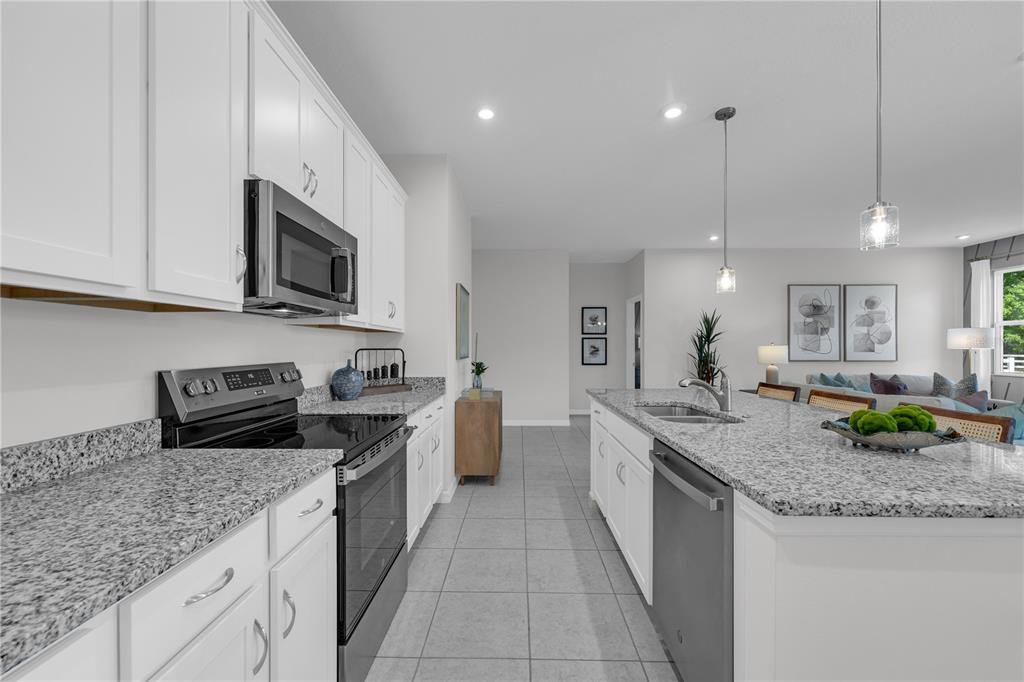 1267 Blue Daze Lane Eustis, FL 32726 - Photo 9 of 34 a kitchen with granite countertop stainless steel appliances a stove sink and microwave