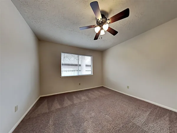 an empty room with a ceiling fan and window