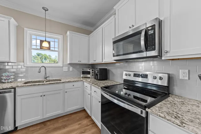 a kitchen with stainless steel appliances granite countertop a stove top oven a sink dishwasher and a refrigerator with wooden floor