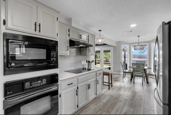 a kitchen with stainless steel appliances a stove a sink cabinets and a wooden floor