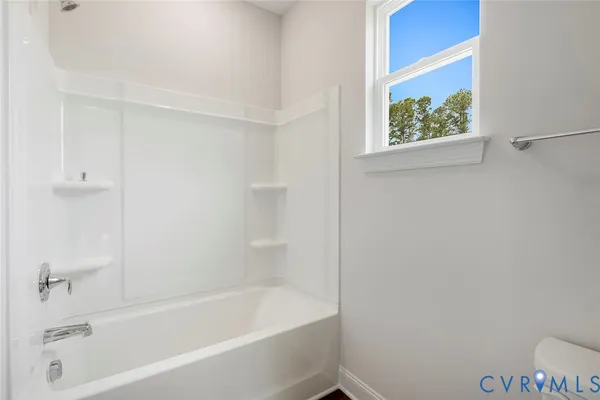 a white bath tub sitting next to a white toilet and vanity