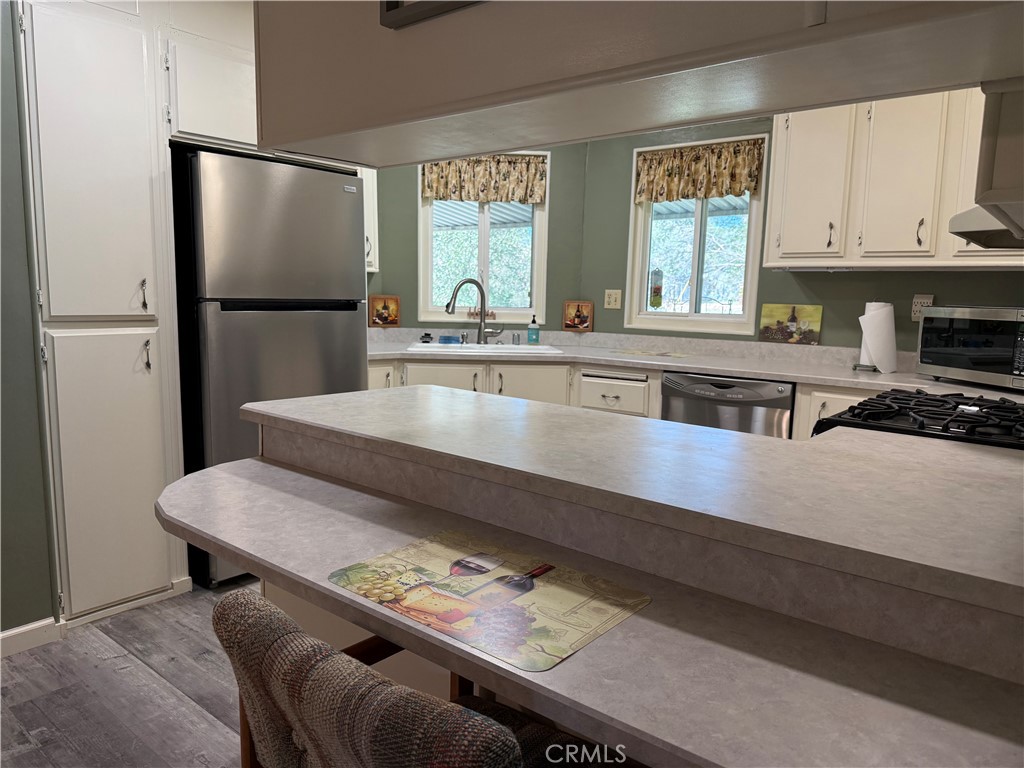 7452-7452 Live Oak Road Corning, CA 96021 - Photo 9 of 19 a kitchen with stainless steel appliances granite countertop a refrigerator a sink dishwasher a stove and white countertops with wooden floor