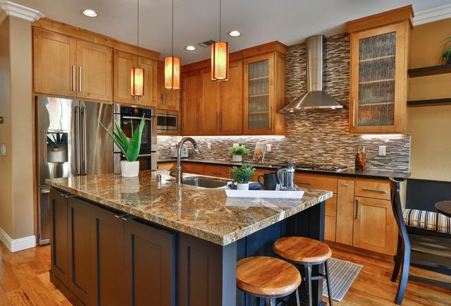 a kitchen with granite countertop a table chairs stove a sink and dishwasher