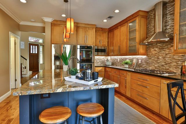 a kitchen with stainless steel appliances granite countertop wooden cabinets a oven and a sink