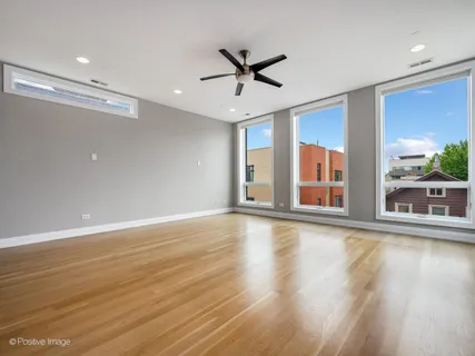 a view of a livingroom with wooden floor a ceiling fan and windows