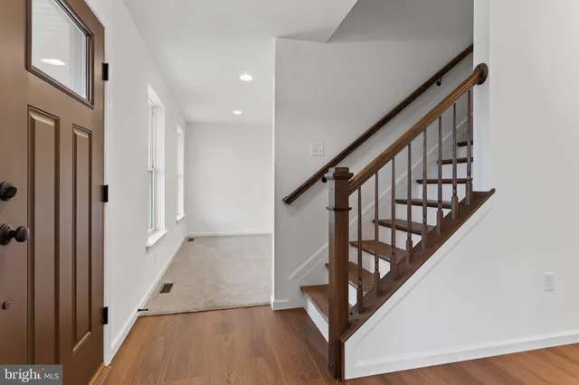 a view of staircase with wooden floor and white walls