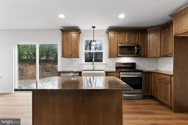 a kitchen with stainless steel appliances granite countertop a stove a sink and a microwave