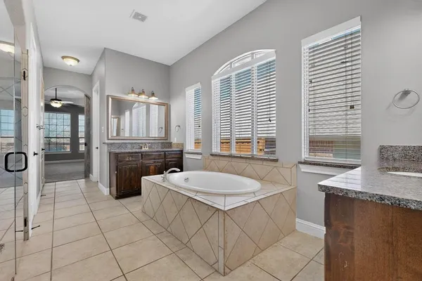 a bathroom with a granite countertop sink a mirror and a bathtub