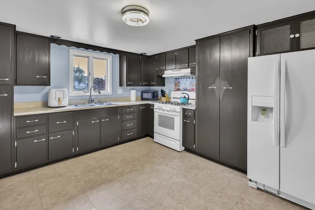 a kitchen with stainless steel appliances granite countertop a refrigerator a sink dishwasher a stove and a refrigerator