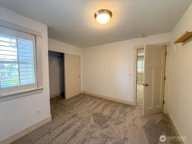 a view of an empty room with closet and a window