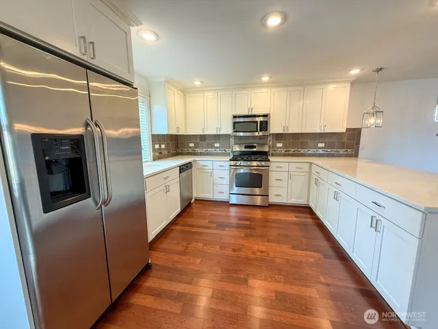 a large kitchen with stainless steel appliances granite countertop a refrigerator and a stove top oven