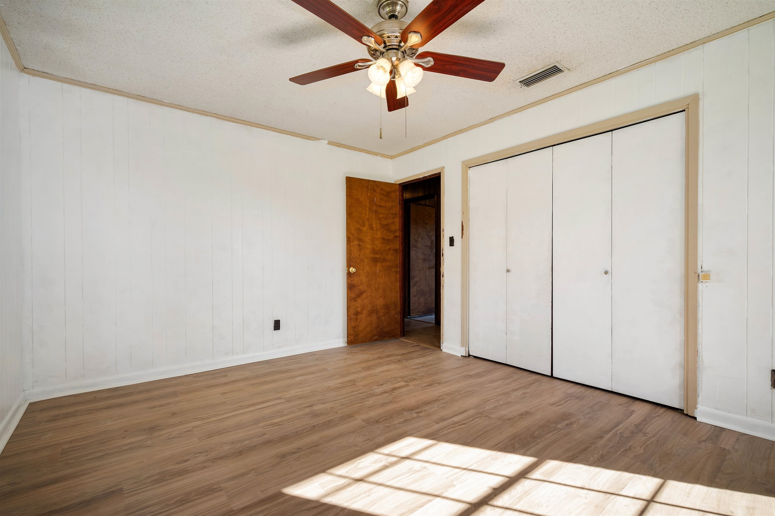 10285 Argyle Road Irvington, AL 36544 - Photo 20 of 28 Unfurnished bedroom featuring wood finished floors, a textured ceiling, crown molding, wood walls, and ceiling fan