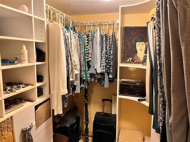 a view of walk in closet with clothes and shoes