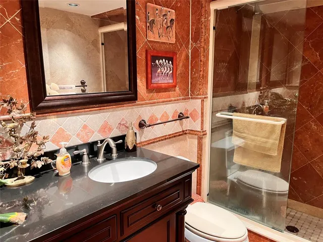 a bathroom with a granite countertop sink mirror vanity and toilet
