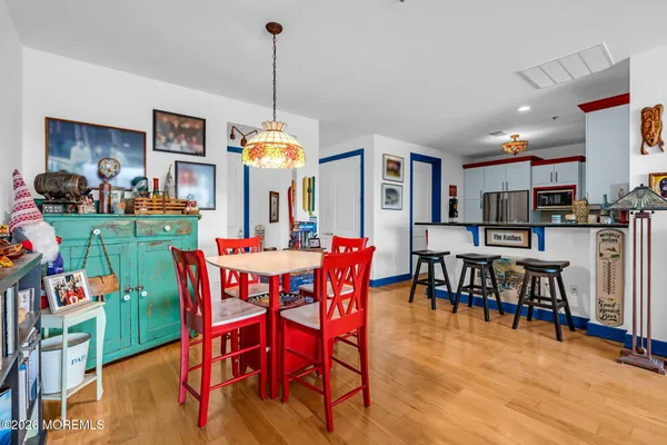 a view of a dining room and livingroom with furniture wooden floor a rug a painting and a chandelier
