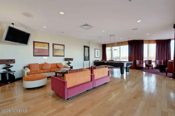 a living room with furniture a large window and wooden floor