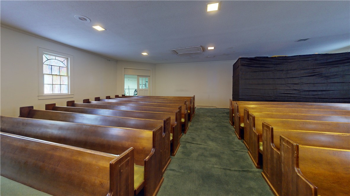 415 Church Street Pendleton, SC 29670 - Photo 6 of 35 Rows of classic wooden pews define this ample gathering space, illuminated by discrete ceiling lights.