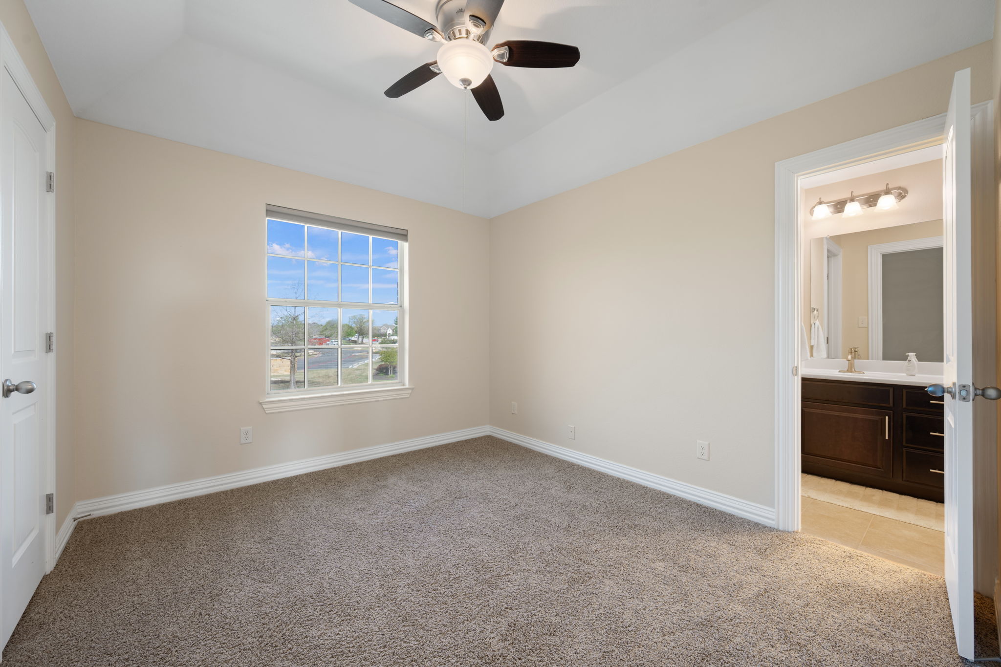 3904 Brean Down Road Pflugerville, TX 78660 - Photo 29 of 40 Unfurnished bedroom featuring light colored carpet, a ceiling fan, a raised ceiling, and connected bathroom