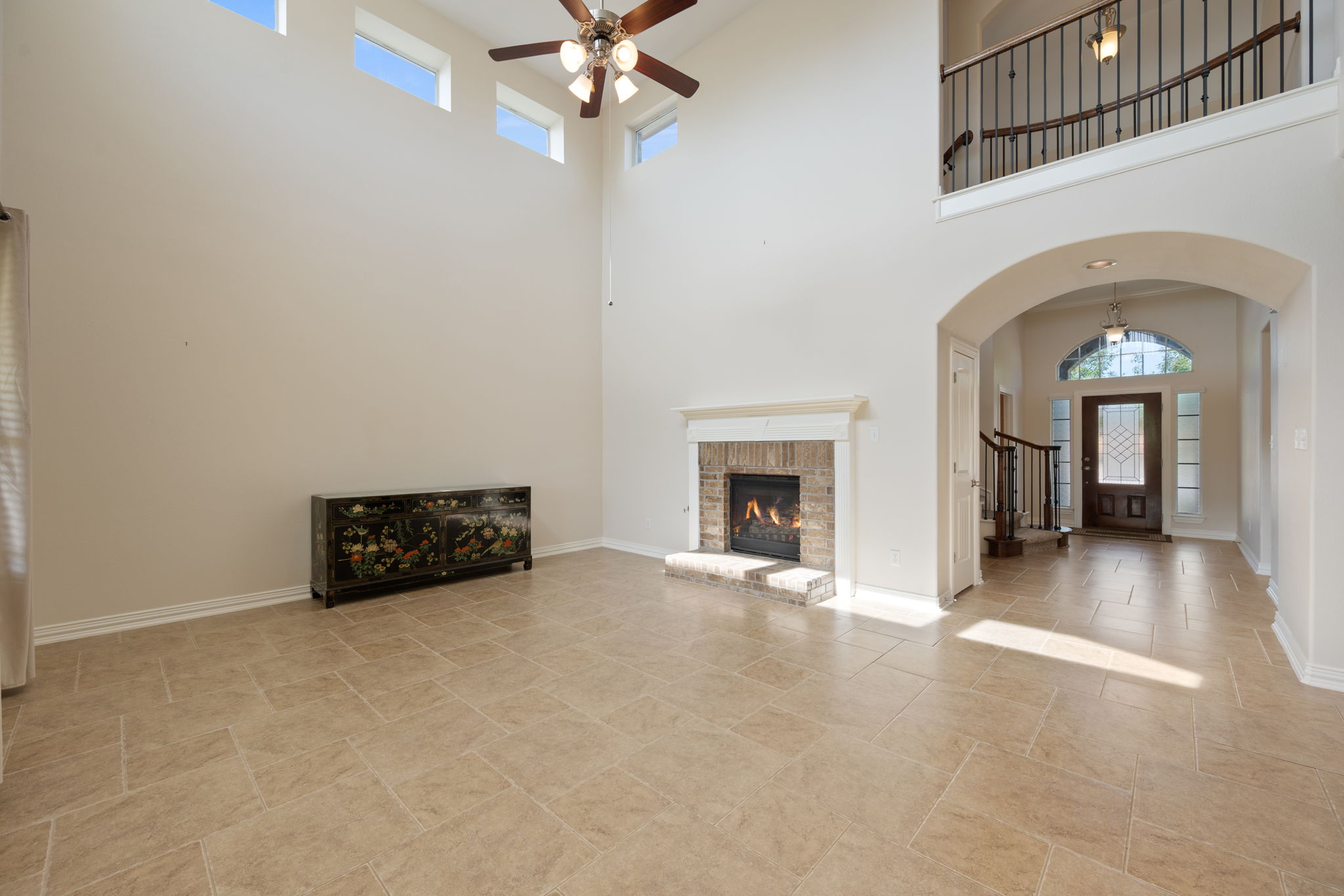 3904 Brean Down Road Pflugerville, TX 78660 - Photo 6 of 40 Unfurnished living room featuring arched walkways, a high ceiling, a ceiling fan, and a brick fireplace