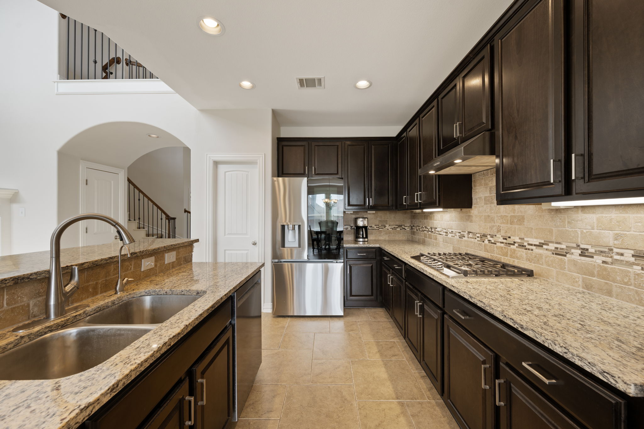 3904 Brean Down Road Pflugerville, TX 78660 - Photo 9 of 40 Kitchen with light stone countertops, stainless steel appliances, dark wood finish cabinetry, and recessed lighting