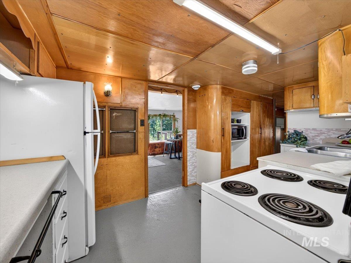 6 Rattlesnake Road Boise City, ID 83716 - Photo 27 of 50 Kitchen featuring full wood-finish wall paneling and ceiling, white countertops, built-in cabinetry, white electric range, and a white refrigerator