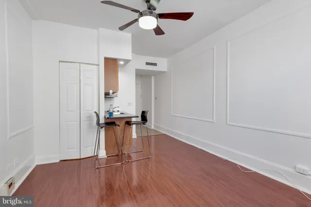a view of a room with wooden floor a ceiling fan and windows