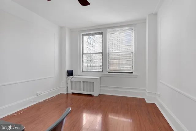 a view of an empty room with a window and wooden floor
