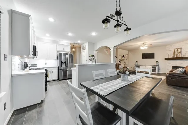 a large kitchen with kitchen island a stove a sink dishwasher a dining table and chairs with wooden floor