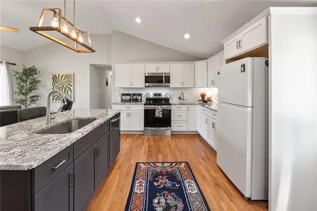 a large kitchen with stainless steel appliances granite countertop a sink stove and refrigerator