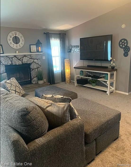 786 Chestnut Street Fowlerville, MI 48836 - Photo 7 of 19 Living area featuring a stone-clad fireplace, carpet flooring, and a window with drapes
