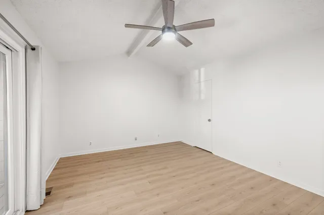 a view of a room with wooden floor and a ceiling fan