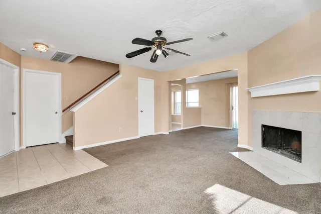 a view of an empty room with chandelier fan and fire place