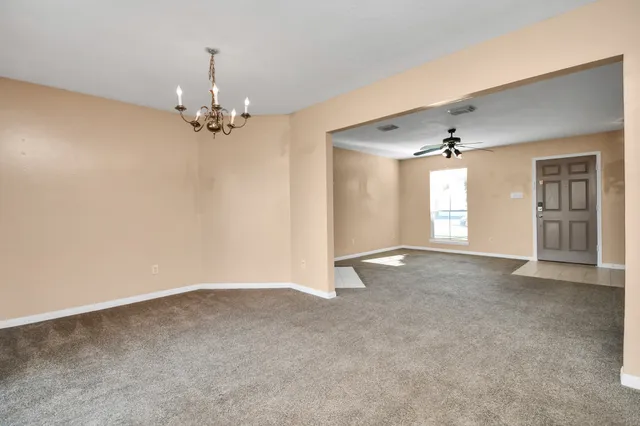 a view of an empty room with chandelier and window