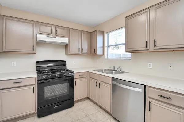 a kitchen with cabinets appliances a sink and a window