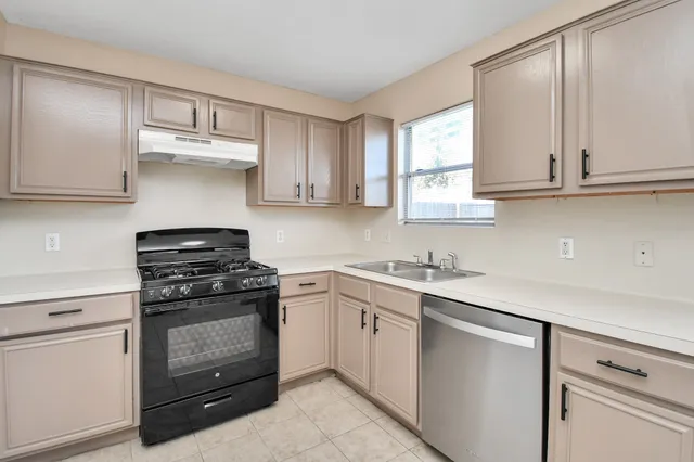 a kitchen with cabinets appliances a sink and a window