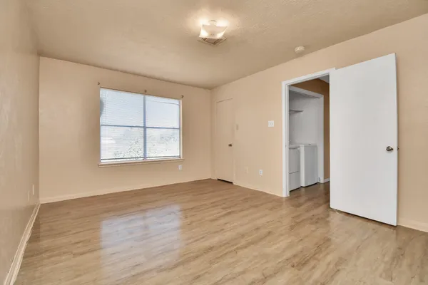 an empty room with wooden floor and windows