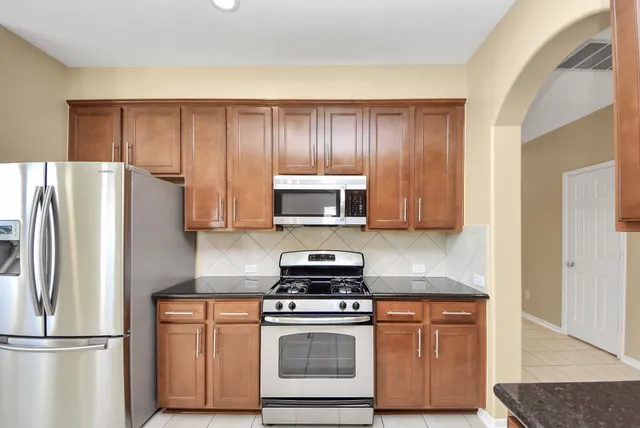 a kitchen with stainless steel appliances granite countertop a stove a sink and a refrigerator