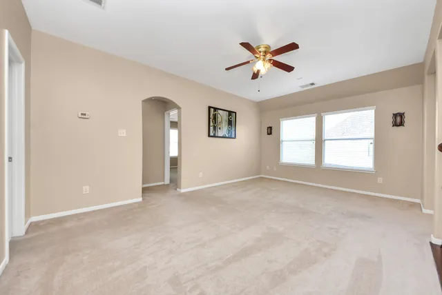 an empty room with windows and fan