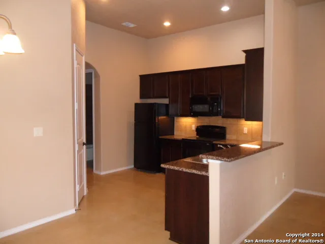 a kitchen with granite countertop cabinets and black appliances