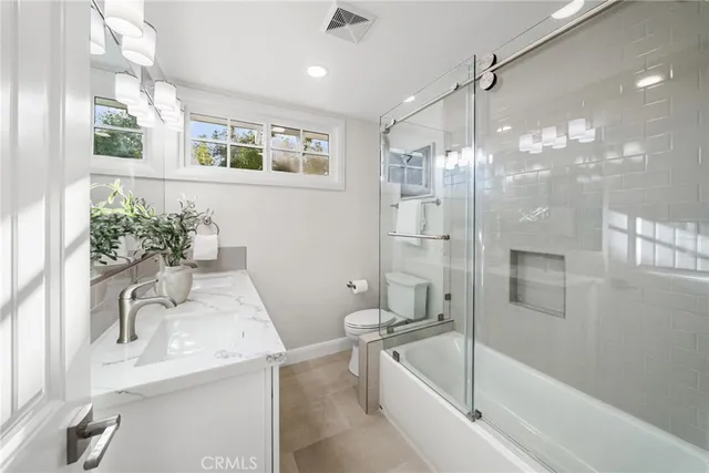 a bathroom with a granite countertop sink a toilet a large mirror and shower