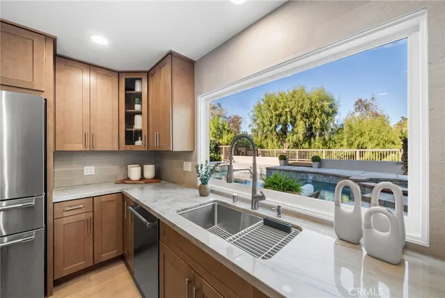 a kitchen with stainless steel appliances granite countertop a sink and a refrigerator